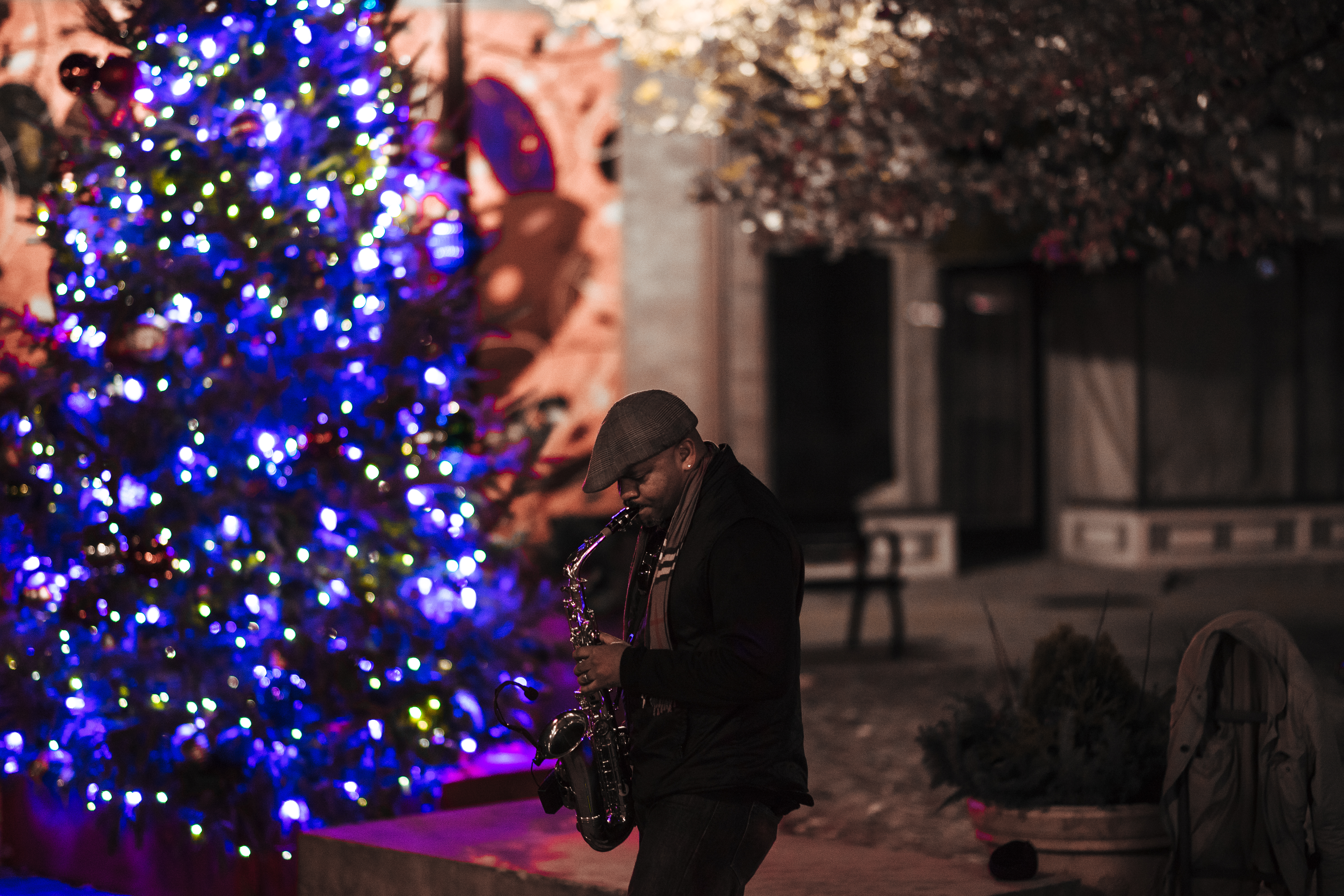 On High Street in Columbus's Short North, a saxophonist performs Holiday Music to welcome in the season next to the neighborhood's Christmas tree. 